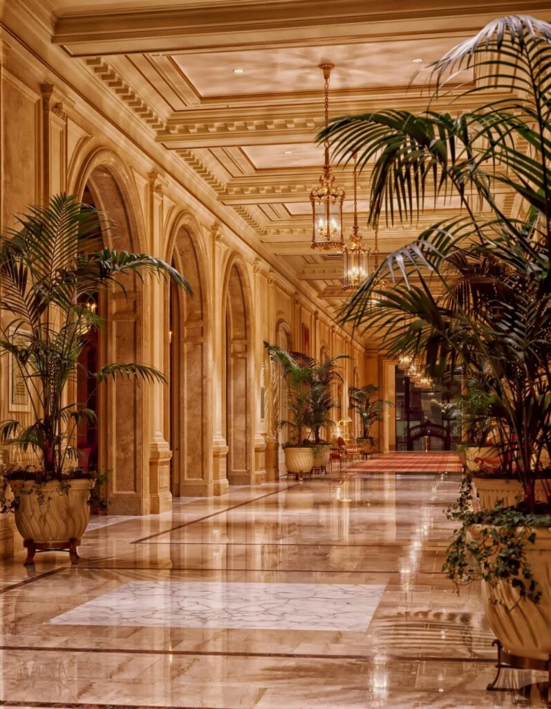 Luxurious hotel lobby featuring elegant lighting and marble flooring, accented by lush indoor plants.